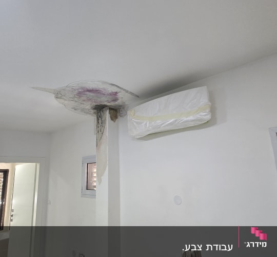 עבודות תיקון שפכטל והכנת קיר לצביעה בחדר עם סולם ומזגן מוגן בניילון